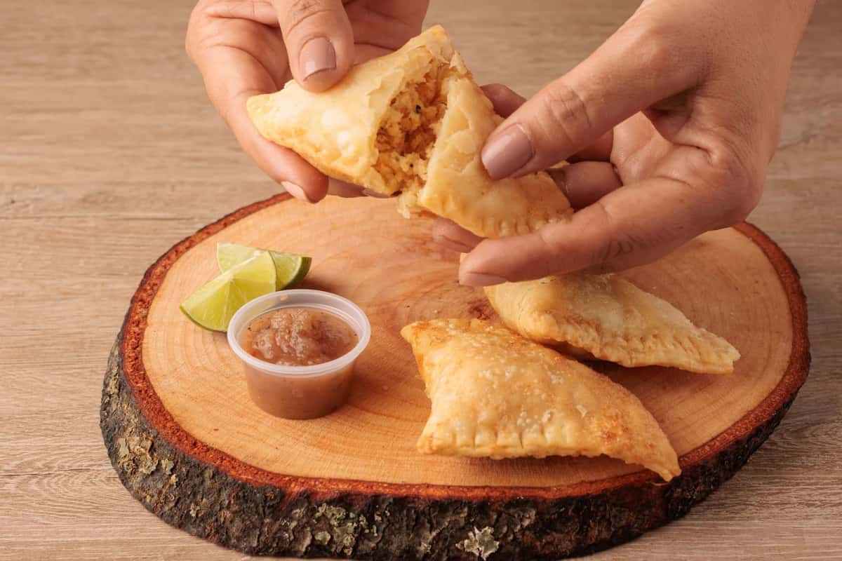 Empanadas colombiennes frites dorées servies avec de l'ají et du citron vert