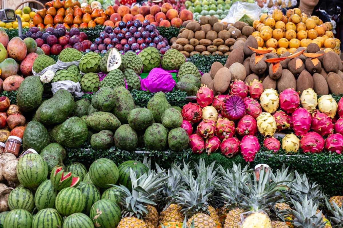 Étal débordant de fruits exotiques colombiens sur un marché : guanábana, pitaya, zapote, tomate de árbol