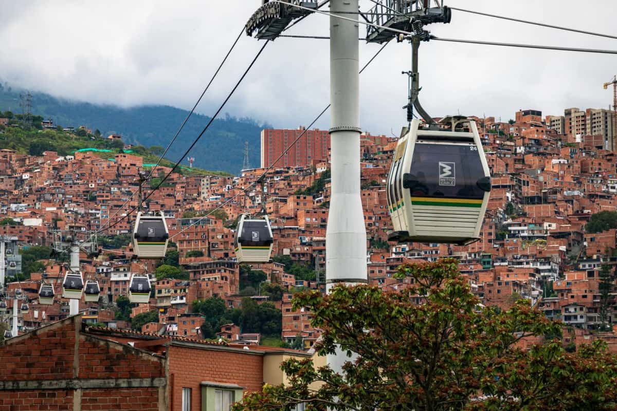 Cabines du metrocable de Medellín survolant les quartiers de brique accrochés à la colline