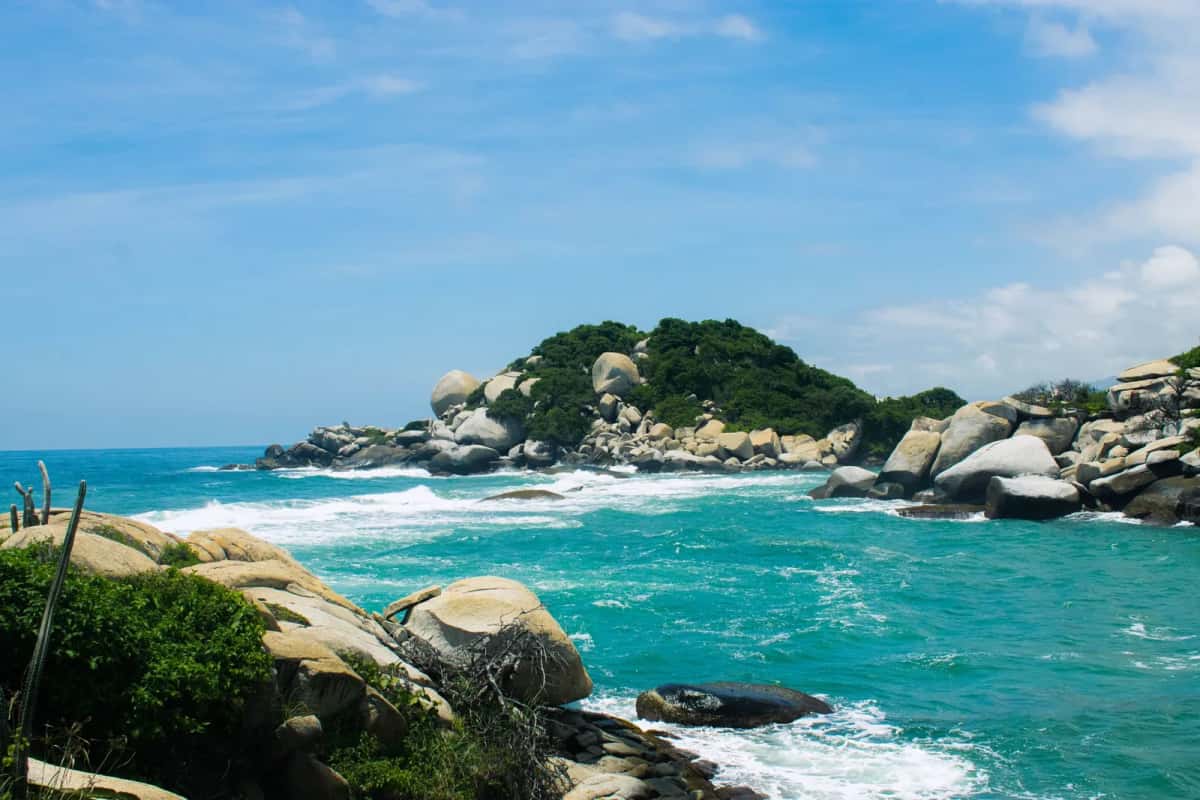 Plage du parc Tayrona en Colombie, eau turquoise et gros rochers de granit sous la végétation tropicale